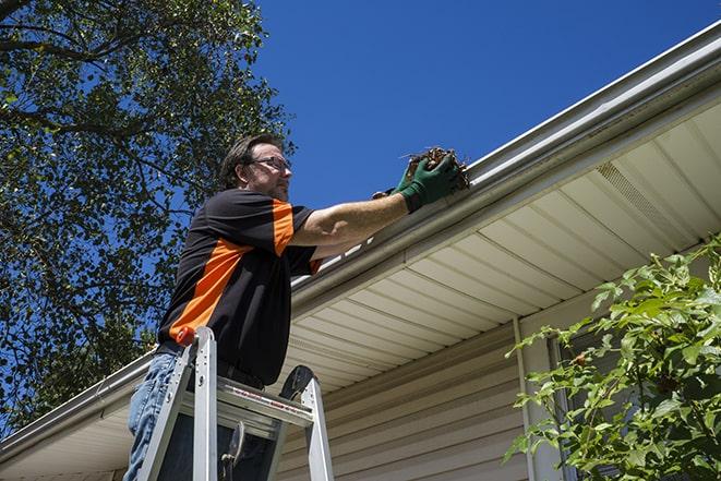 man installing new gutter system on a roof in Avon